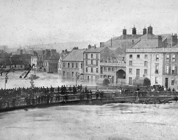 Crowds gather on a bridge to witness flooding